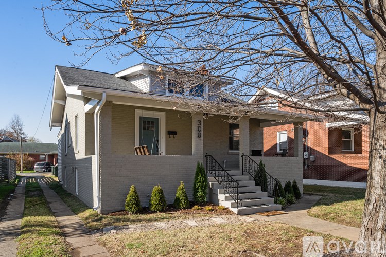 A house with a grey front and a tree in front.