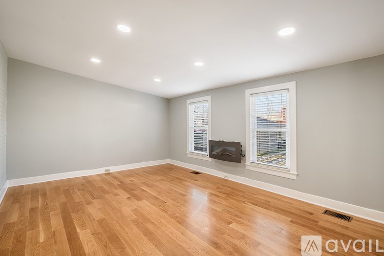 A room with wooden flooring and a window with blinds.