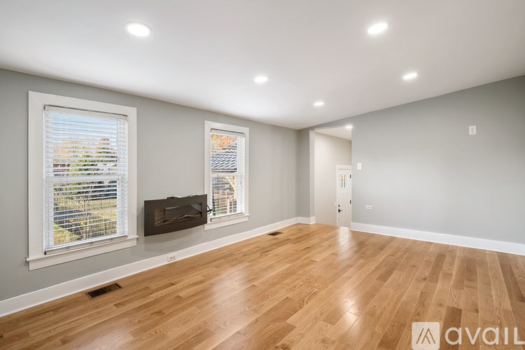 A spacious room with wooden floors and two windows.