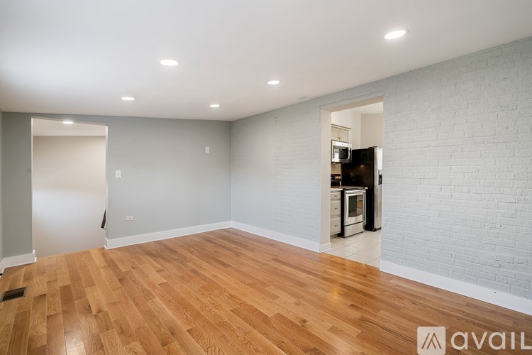 A spacious room with wooden flooring and white walls.