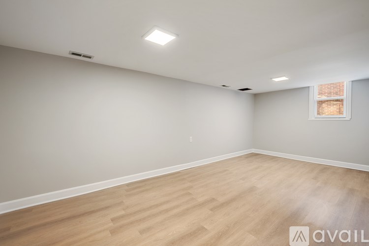 A spacious room with wooden flooring and a window.