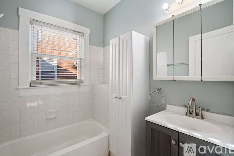A bathroom with a tub, sink, and mirror.