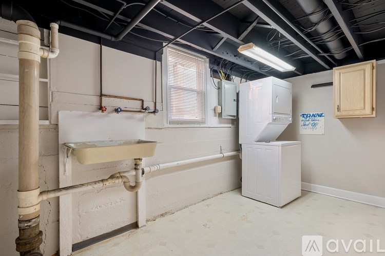 A room with a sink, a fridge, and a window.