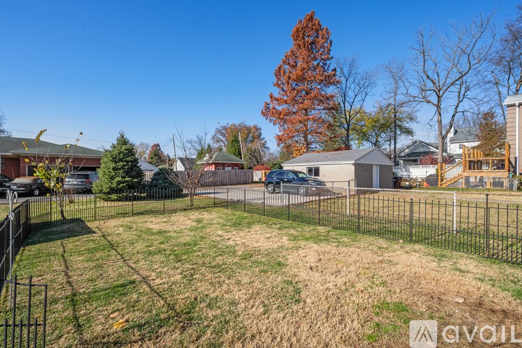 A grassy field with a fence and houses in the background.