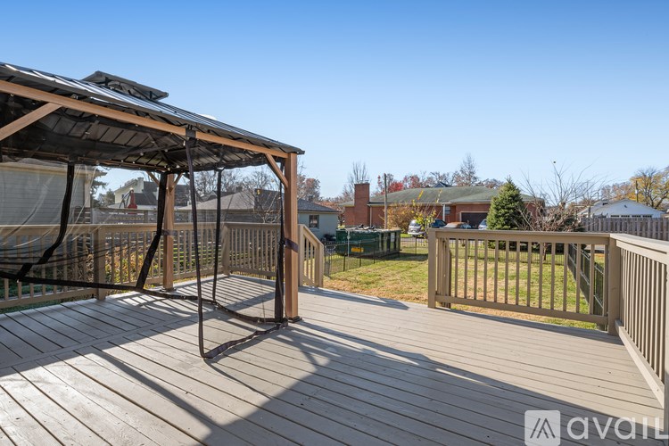 A wooden deck with a pergola and a fence in the background.