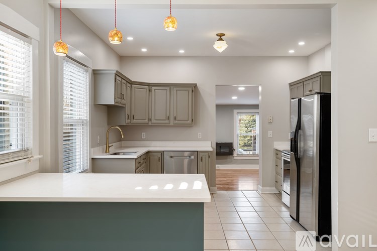 A kitchen with a refrigerator on the right and a sink in the middle.