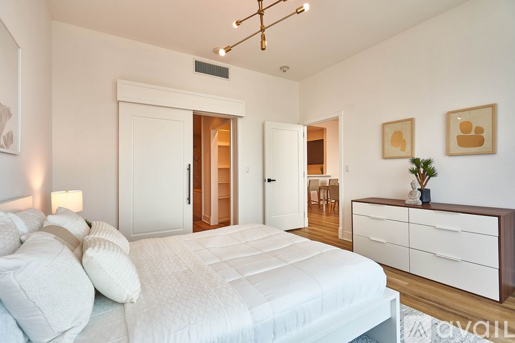 A bedroom with a large bed, a dresser, and a ceiling light.