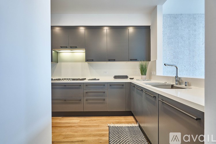 A modern kitchen with stainless steel appliances and wooden flooring.