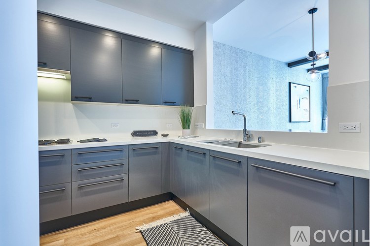A modern kitchen with grey cabinets and a white countertop.