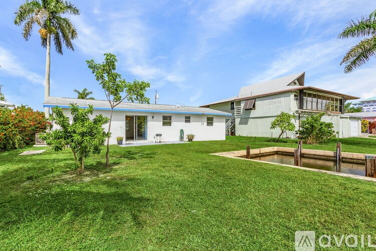 A house with a well-maintained lawn and a palm tree in front.