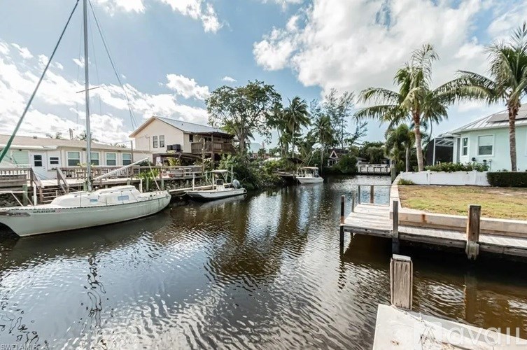 A serene waterfront scene with boats docked and houses in the background.