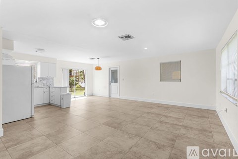 A spacious living room with a kitchen area in the background.
