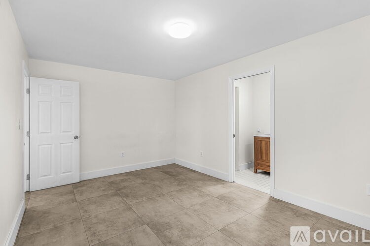 A room with a white door and a wooden stool.