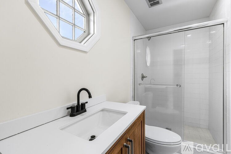 A modern bathroom with a white sink and a glass shower stall.