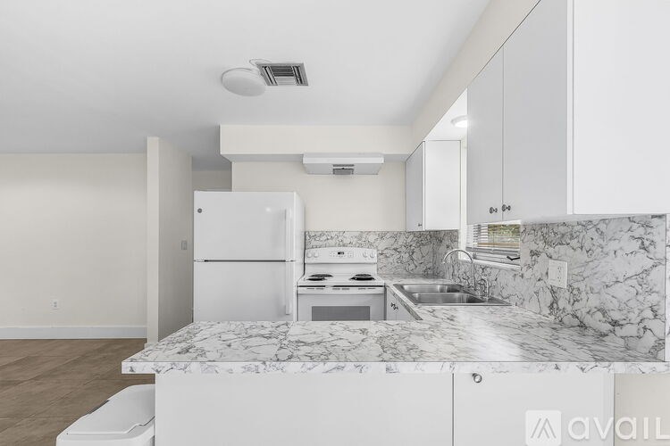 A kitchen with marble countertops and a white refrigerator.