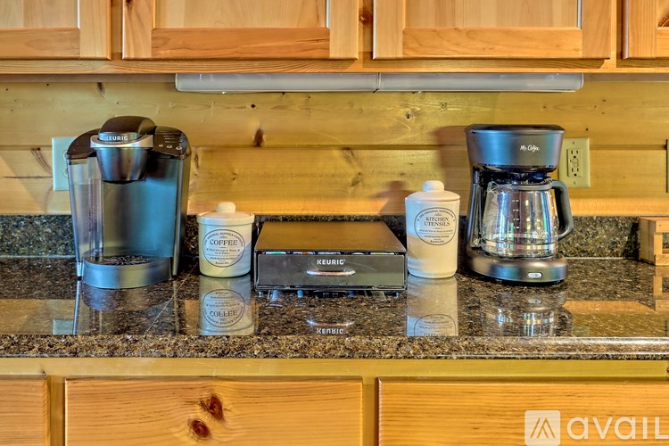 A coffee maker, a bottle of creamer, and a bottle of coffee are on a counter.