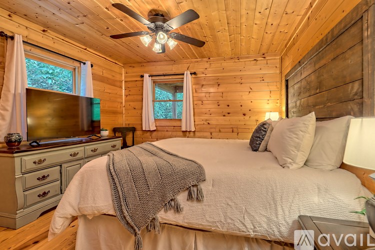 A bedroom with a bed, a dresser, and a ceiling fan.