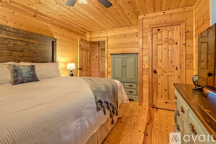 A bedroom with wooden walls and a bed with a white comforter.