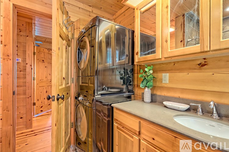 A wooden kitchen with a stainless steel refrigerator and a washer and dryer built into the cabinetry.