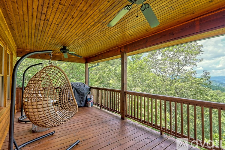 A wooden deck with a hanging chair and a ceiling fan.