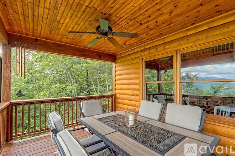A wooden deck with a table and chairs overlooking a forest.