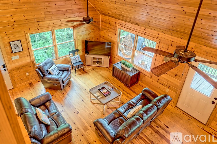 A living room with leather couches and a ceiling fan.