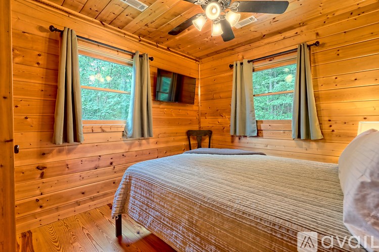 A bedroom with a bed, a ceiling fan, and a window with curtains.