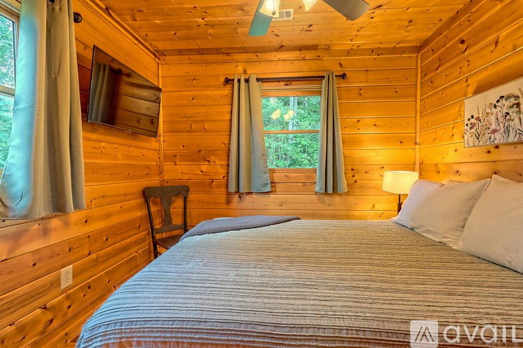 A bedroom with a bed, a chair, and a window with curtains.