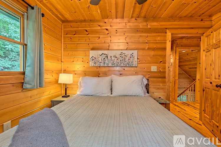 A bedroom with wooden walls and a bed with a white comforter.