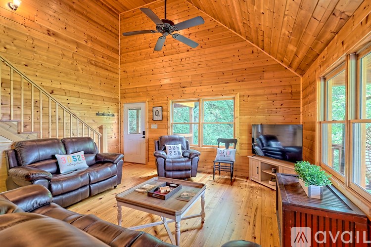 A living room with a wood ceiling and a fan.