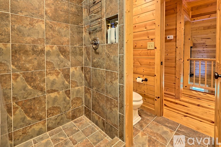 A bathroom with a tiled shower and wooden walls.