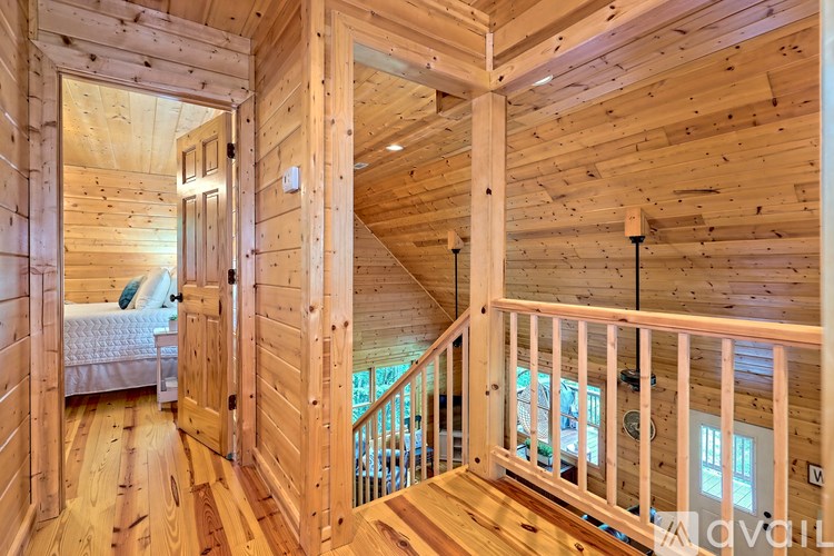 A wooden staircase with a railing leads up to a bedroom with a bed and a window.