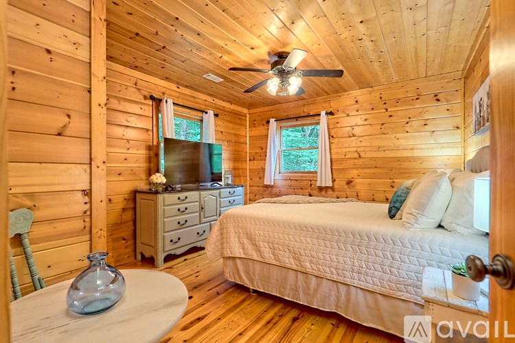 A bedroom with a bed, dresser, and chair in a wooden cabin.