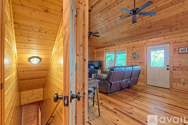 A wooden cabin with a couch and a fan.
