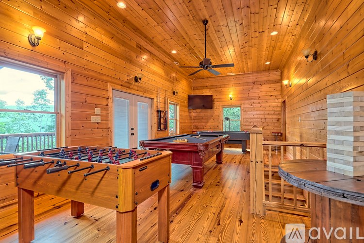 A foosball table is in the middle of a room with a pool table and a TV.