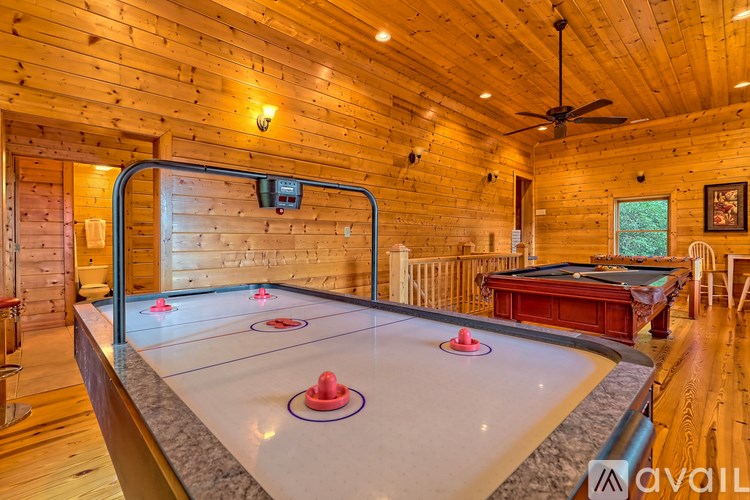 A pool table in a room with wooden walls and a ceiling fan.