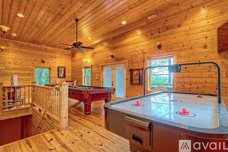 A pool table in a room with wooden walls and a ceiling fan.