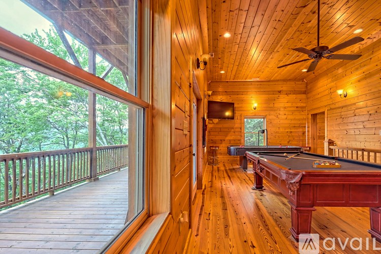 A pool table is in the middle of a room with wood floors and a ceiling fan.