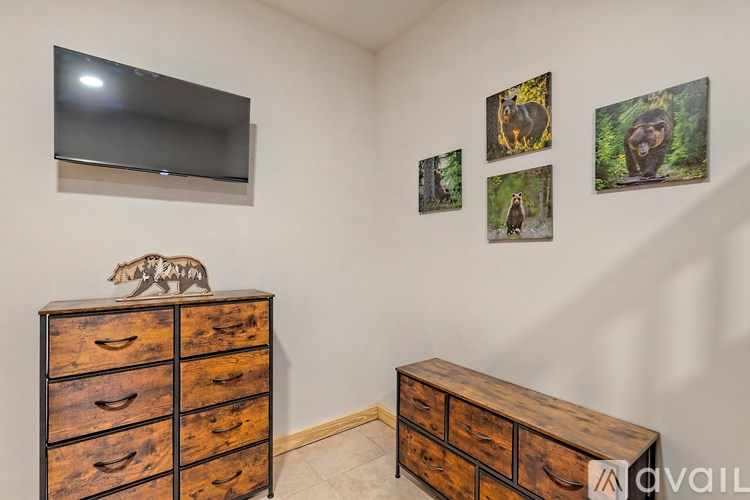 A room with a dresser and a flat screen TV mounted on the wall.