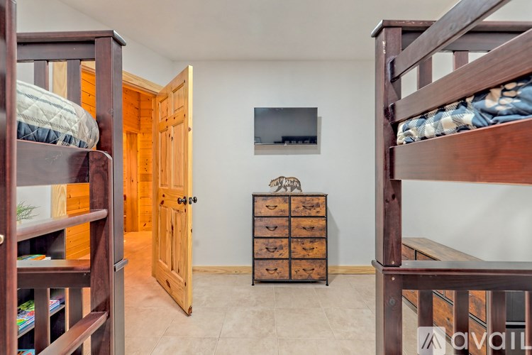 A room with bunk beds, a dresser, and a TV mounted on the wall.