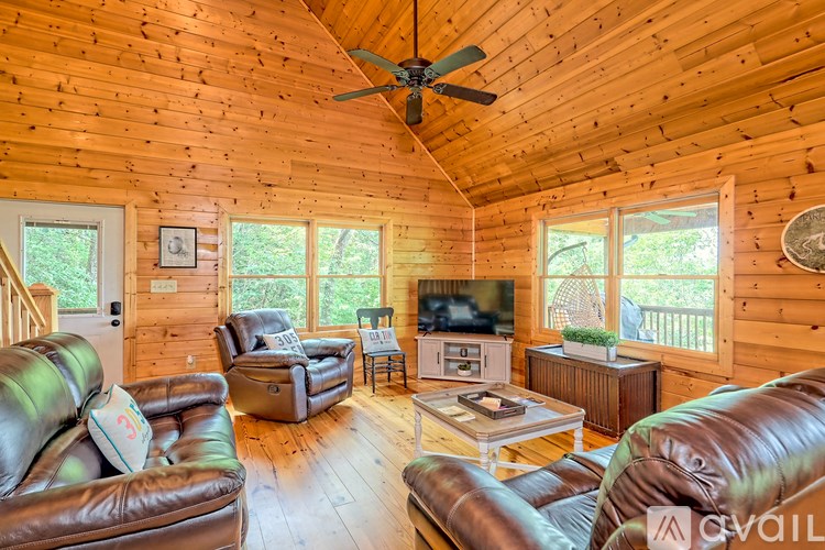 A living room with a brown leather couch and a wooden ceiling.