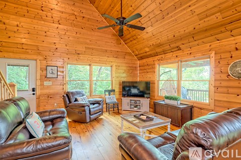 A living room with a brown leather couch and a wooden ceiling.
