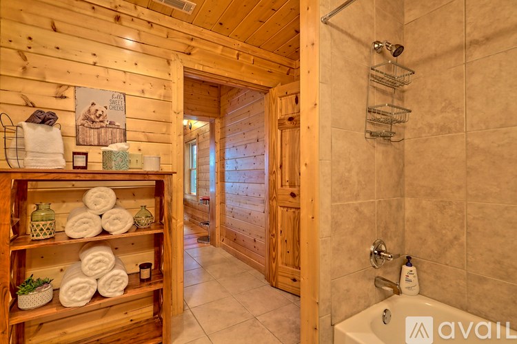 A bathroom with a wooden shelf holding towels and a picture of a bear on the wall.
