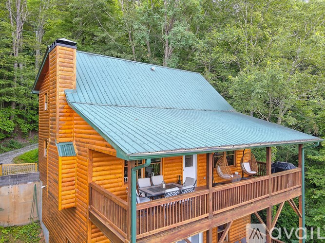A wooden cabin with a green roof is surrounded by trees.