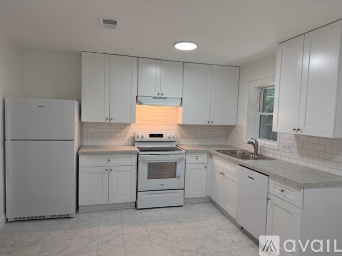 A kitchen with white appliances and cabinets.