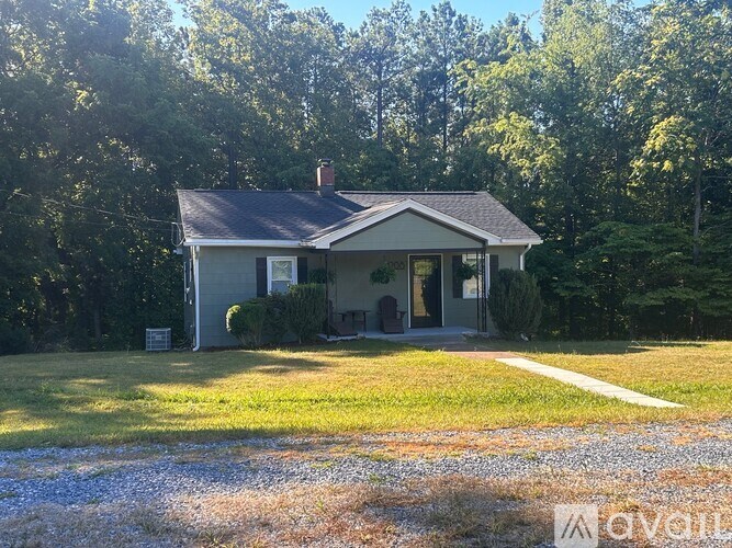 A house with a grey roof and a white sign in front of it.