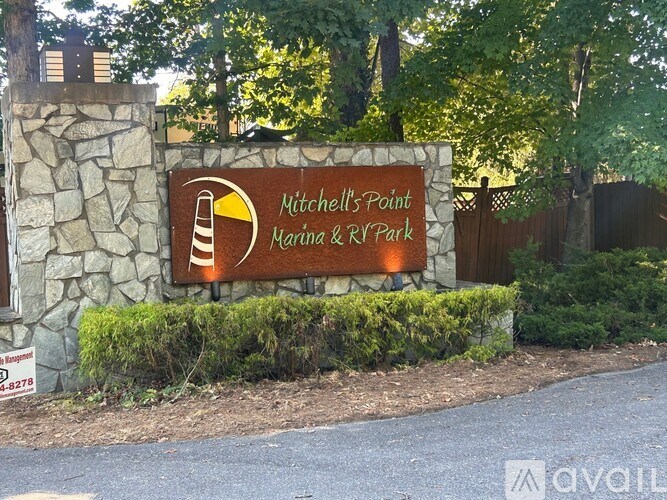 A sign for Mitchell's Point Marina & RV Park is displayed in front of a stone wall.