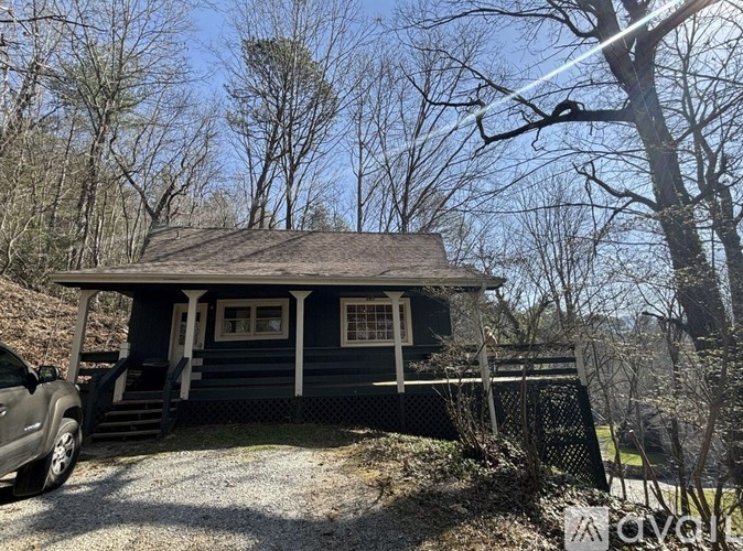 A small house with a porch and a car parked in front.