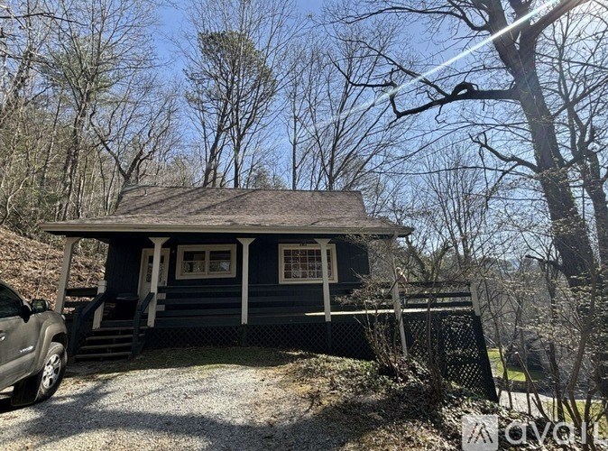 A small house with a porch and a car parked in front.