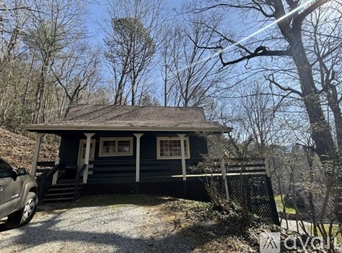 A small house with a porch and a car parked in front.